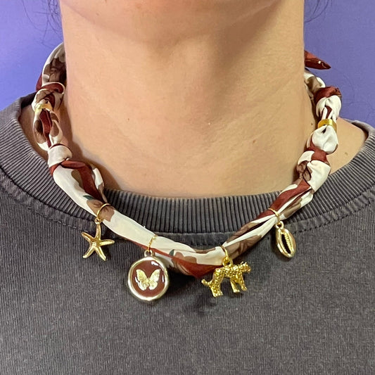 Collar artesanal con dije dorado y pañuelo trenzado, diseño bohemio hecho a mano por Hilma.