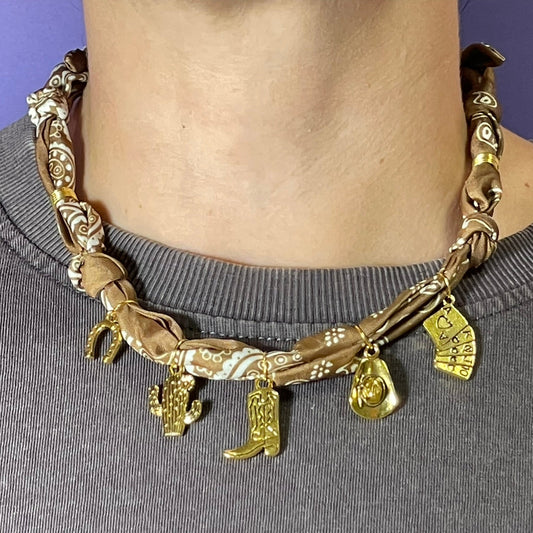 Collar artesanal con dije dorado y pañuelo trenzado, diseño bohemio hecho a mano por Hilma.