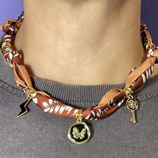 Collar artesanal con dije dorado y pañuelo trenzado, diseño bohemio hecho a mano por Hilma.