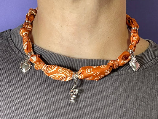 Collar artesanal con dije dorado y pañuelo trenzado, diseño bohemio hecho a mano por Hilma.
