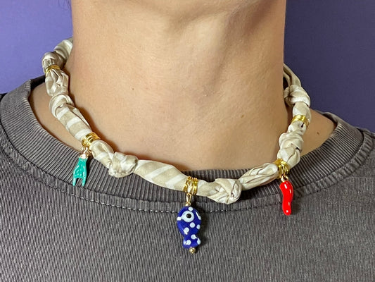 Collar artesanal con dije dorado y pañuelo trenzado, diseño bohemio hecho a mano por Hilma.