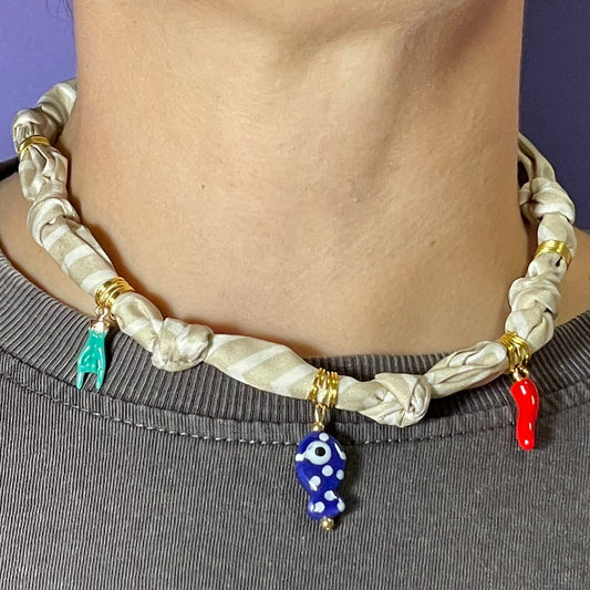 Collar artesanal con dije dorado y pañuelo trenzado, diseño bohemio hecho a mano por Hilma.