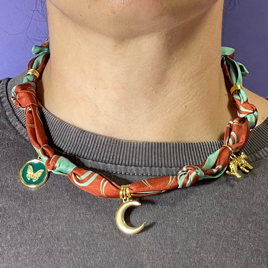 Collar artesanal con dije dorado y pañuelo trenzado, diseño bohemio hecho a mano por Hilma.
