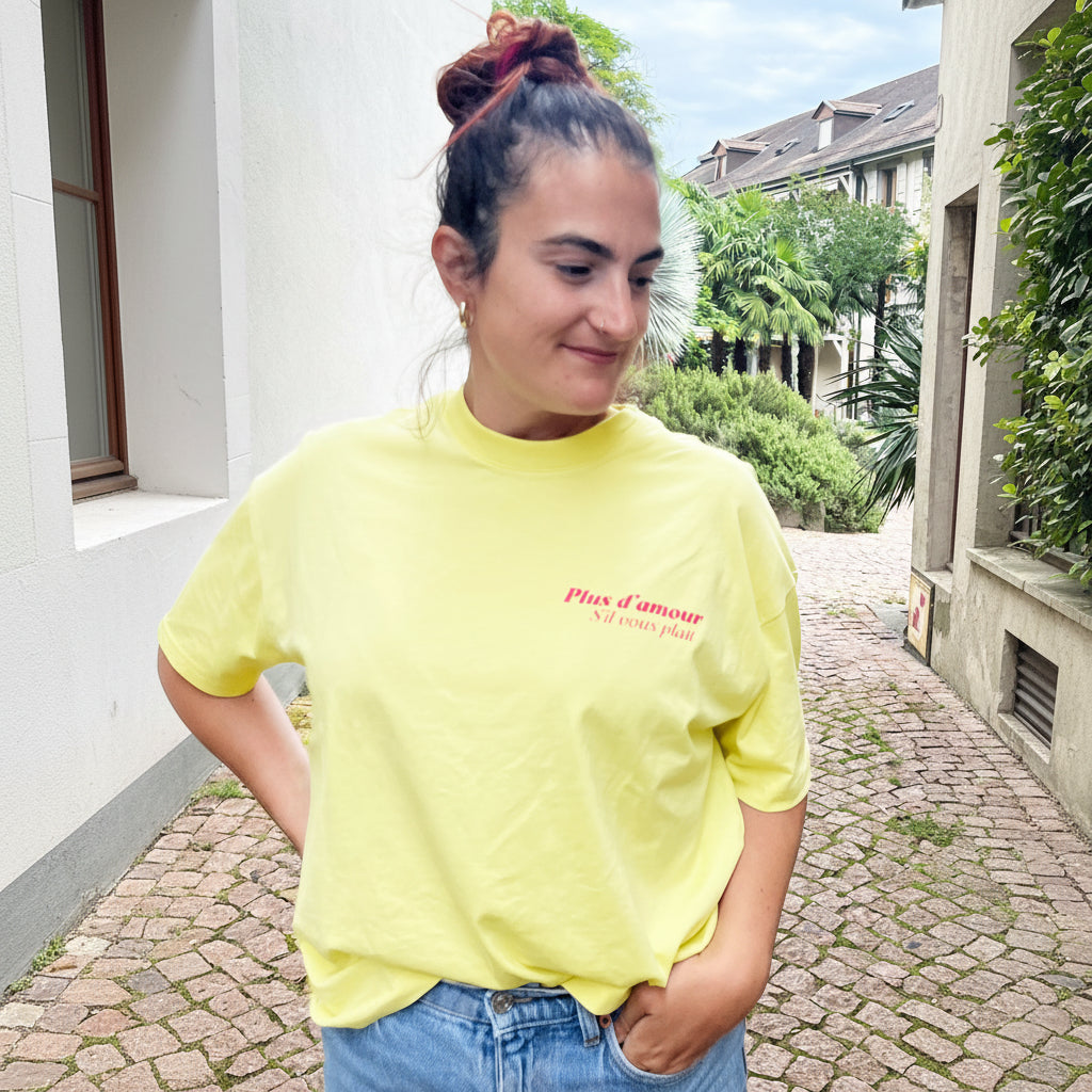 Camiseta boxy amarilla de algodón orgánico con mensaje Plus d'amour s'il vous plait en rosa flúor Hilma Studio