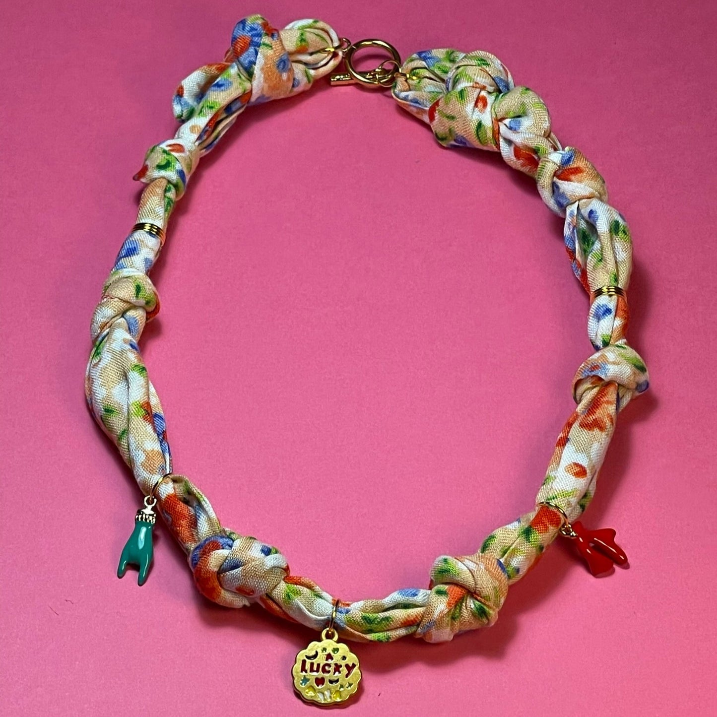 Collar artesanal con dije dorado y pañuelo trenzado, diseño bohemio hecho a mano por Hilma.