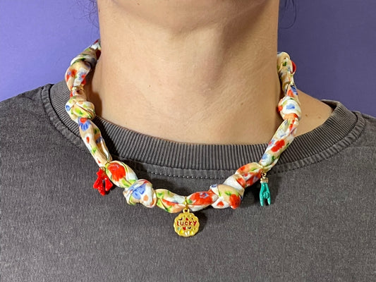 Collar artesanal con dije dorado y pañuelo trenzado, diseño bohemio hecho a mano por Hilma.