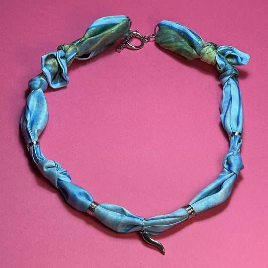 Collar artesanal con dije dorado y pañuelo trenzado, diseño bohemio hecho a mano por Hilma.