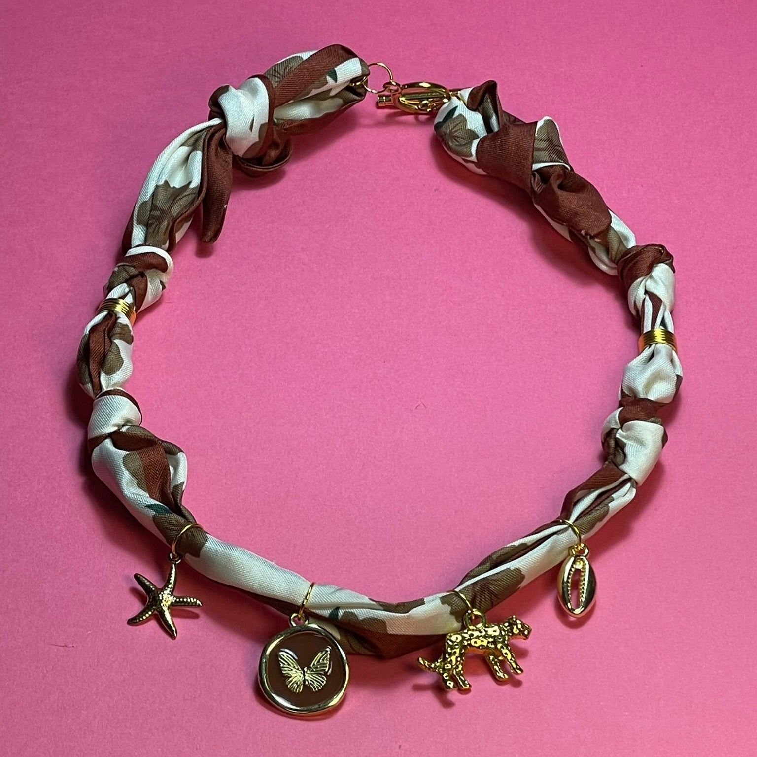 Collar artesanal con dije dorado y pañuelo trenzado, diseño bohemio hecho a mano por Hilma.