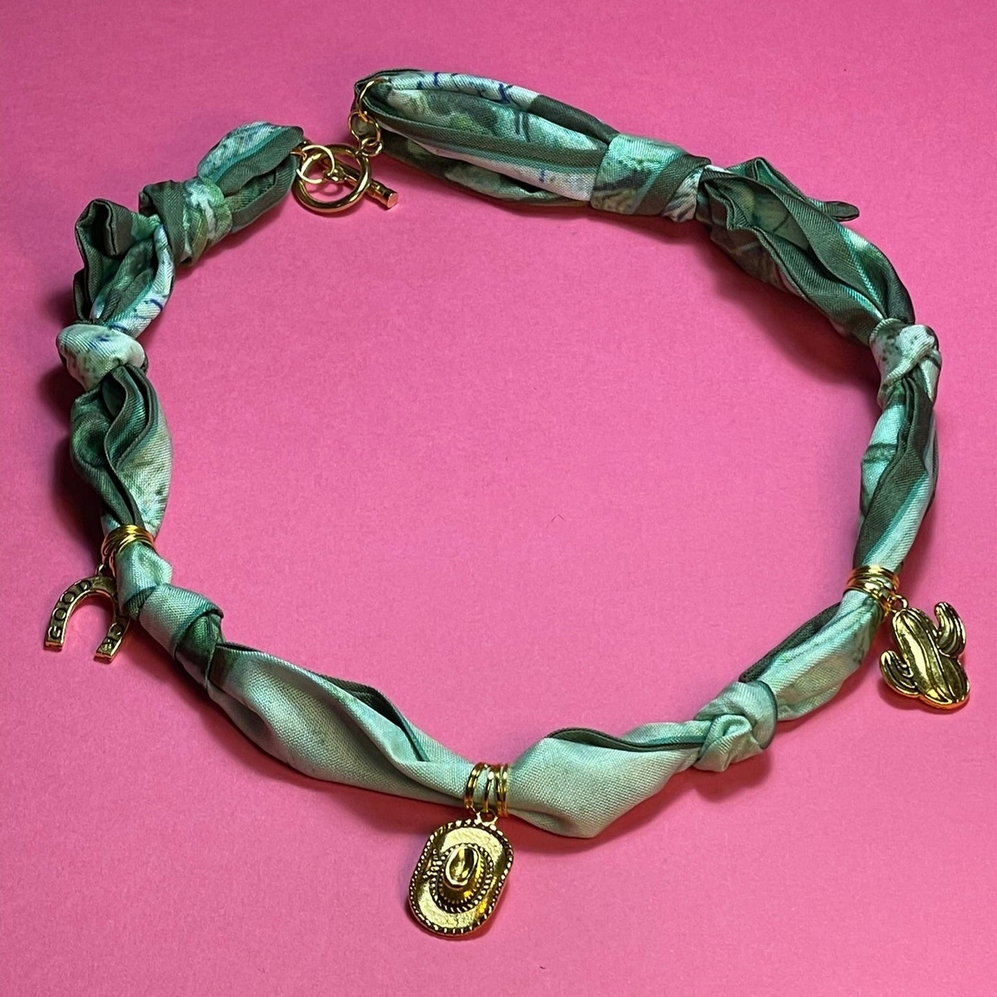 Collar artesanal con dije dorado y pañuelo trenzado, diseño bohemio hecho a mano por Hilma.