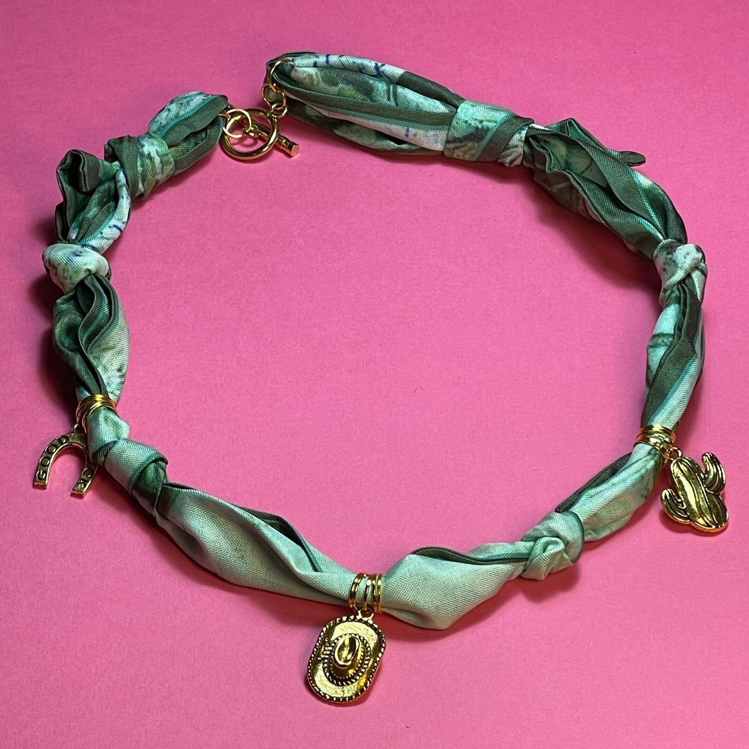 Collar artesanal con dije dorado y pañuelo trenzado, diseño bohemio hecho a mano por Hilma.