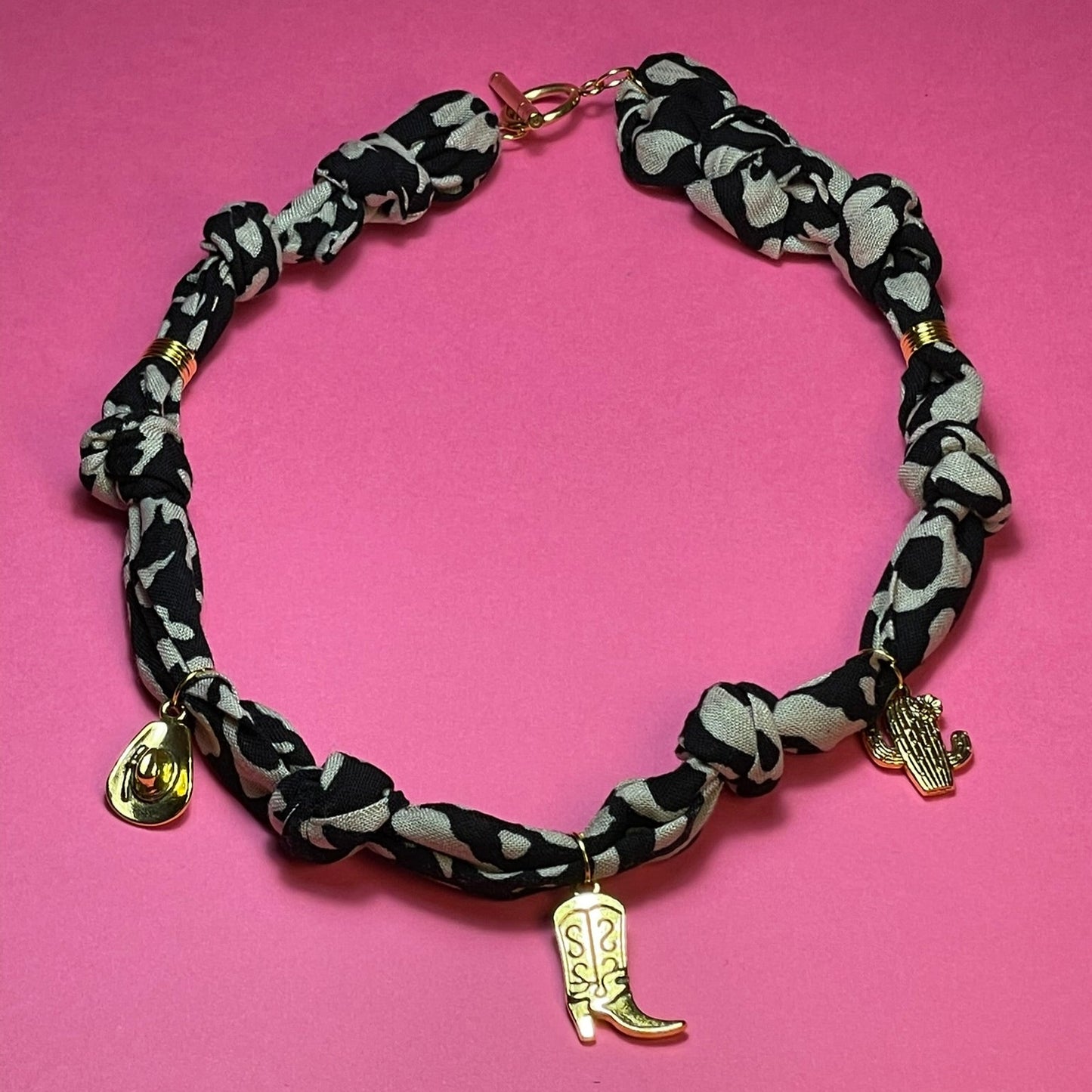 Collar artesanal con dije dorado y pañuelo trenzado, diseño bohemio hecho a mano por Hilma.