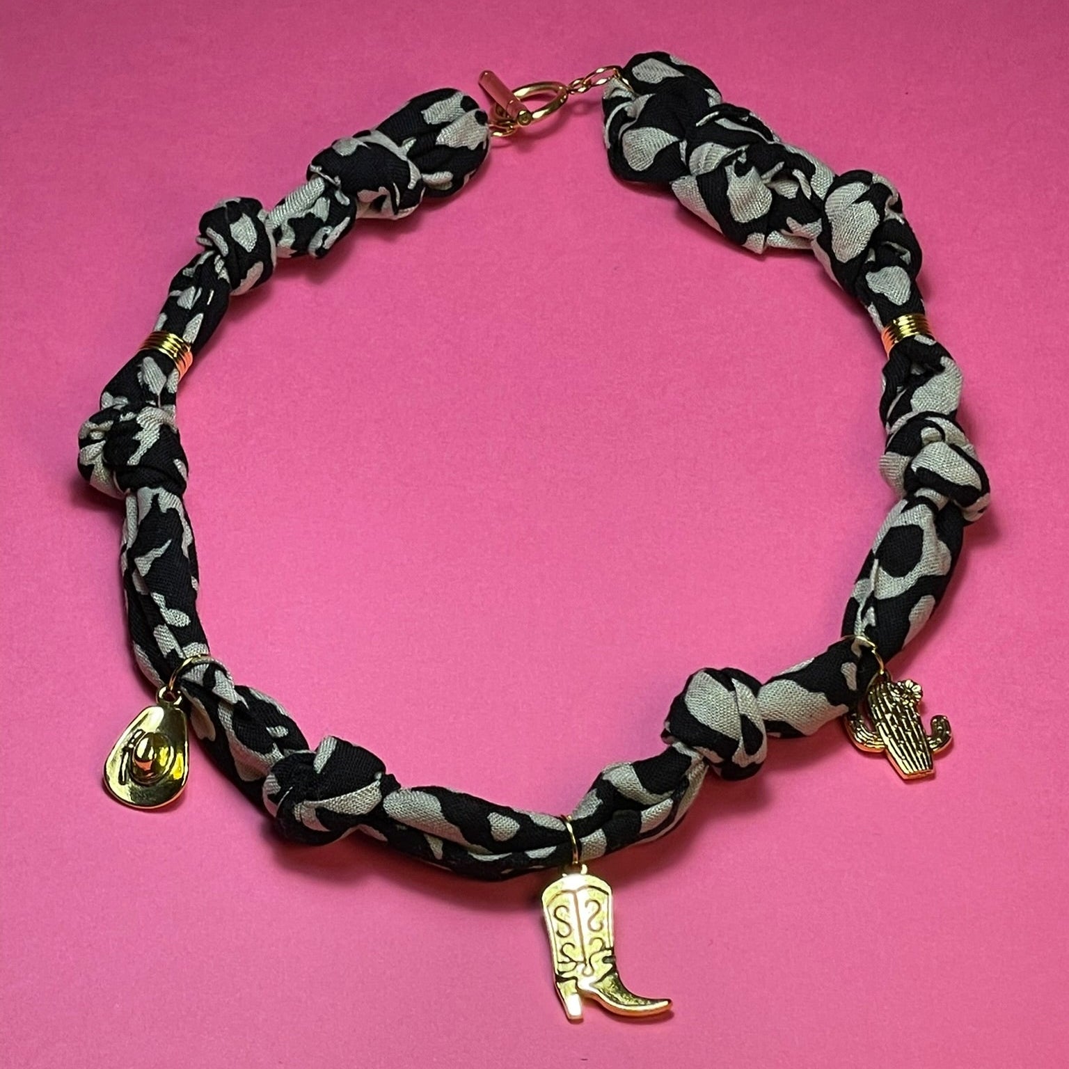 Collar artesanal con dije dorado y pañuelo trenzado, diseño bohemio hecho a mano por Hilma.