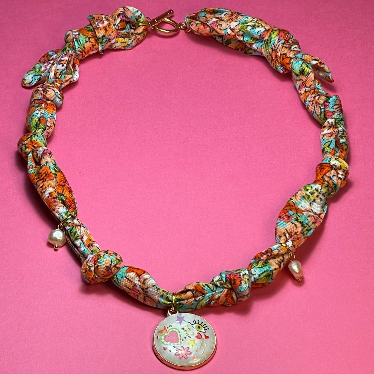 Collar artesanal con dije dorado y pañuelo trenzado, diseño bohemio hecho a mano por Hilma.