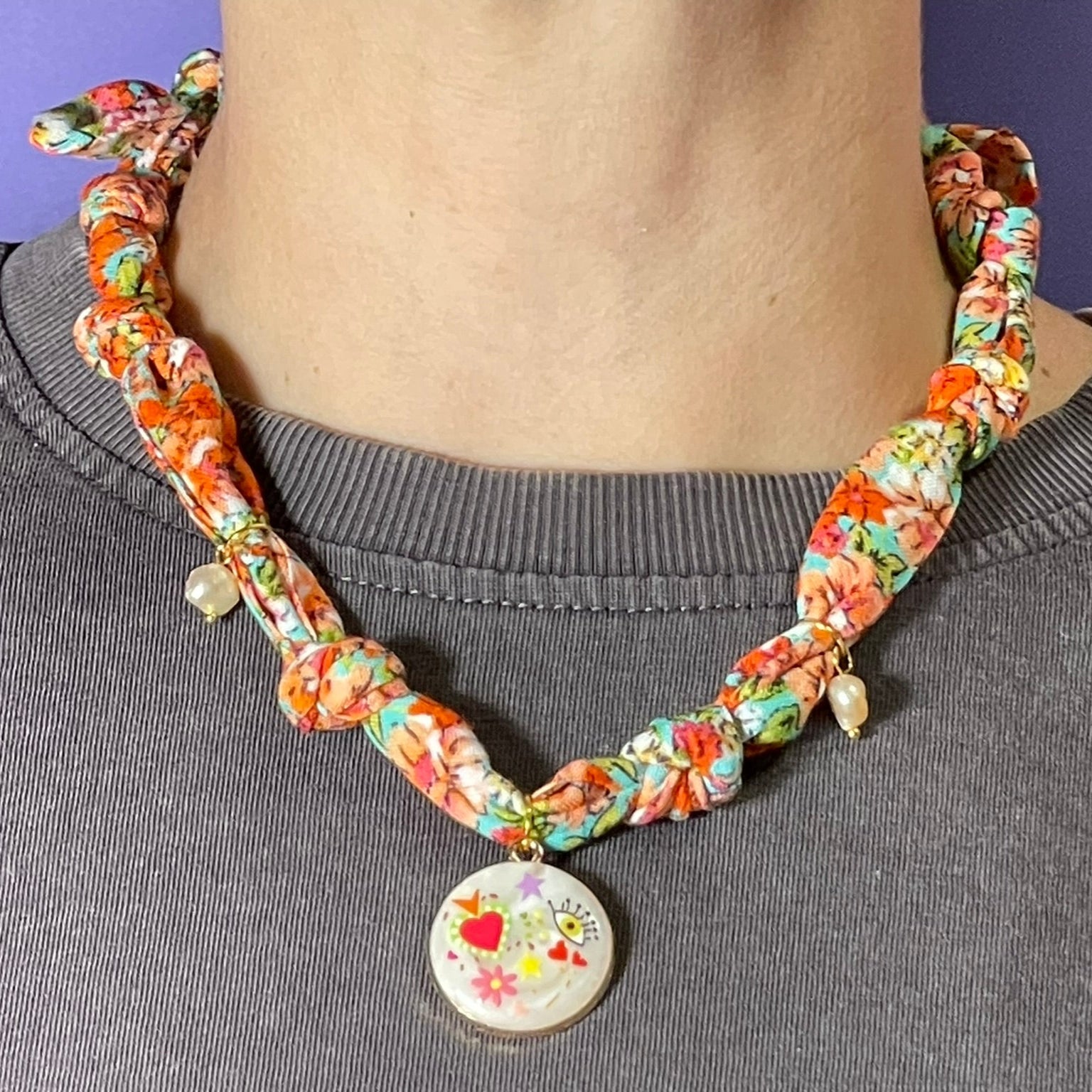 Collar artesanal con dije dorado y pañuelo trenzado, diseño bohemio hecho a mano por Hilma.