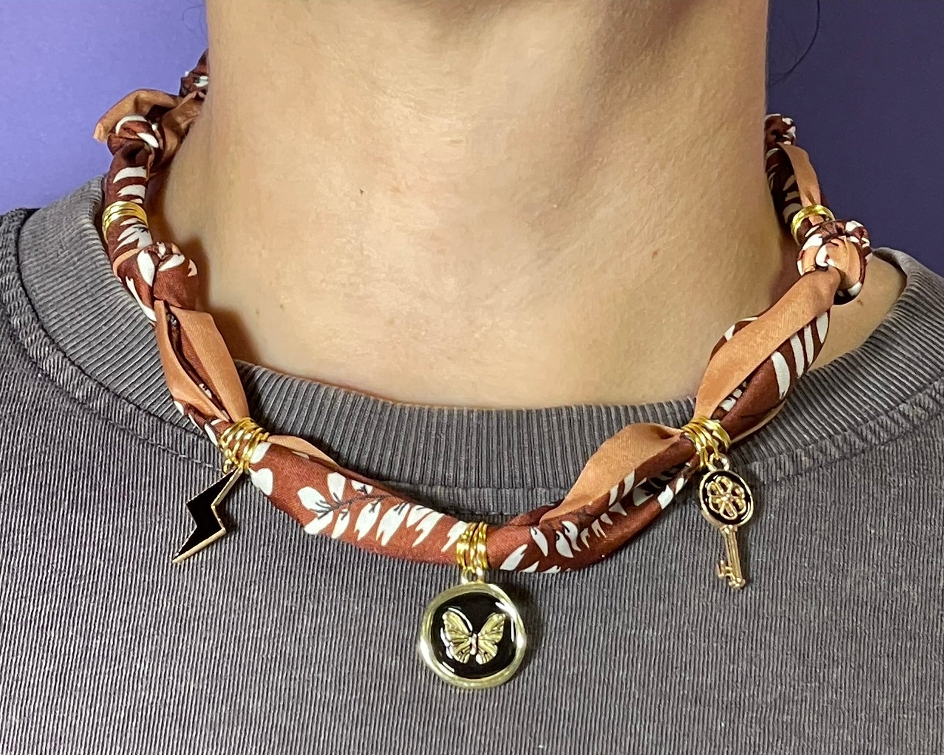 Collar artesanal con dije dorado y pañuelo trenzado, diseño bohemio hecho a mano por Hilma.