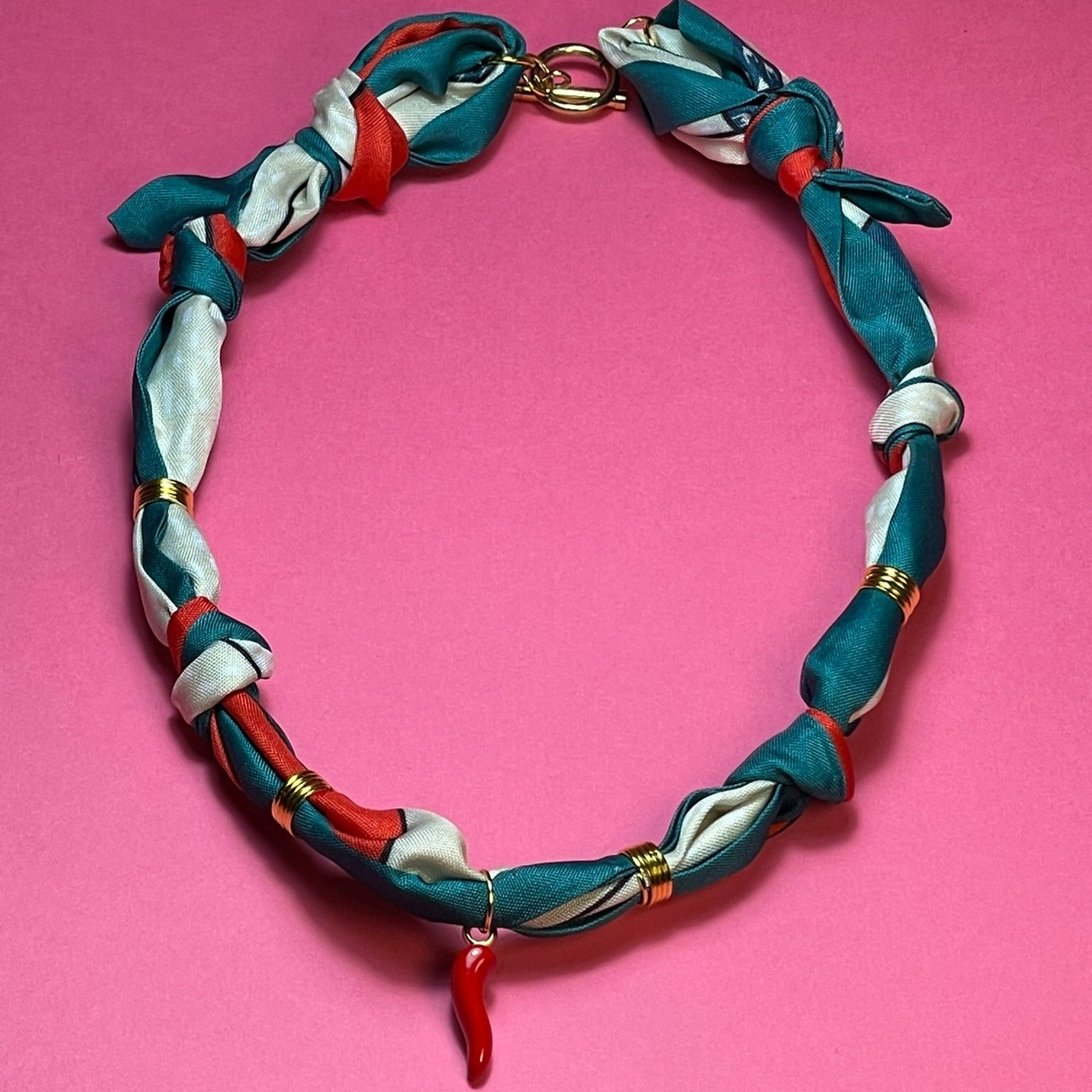 Collar artesanal con dije dorado y pañuelo trenzado, diseño bohemio hecho a mano por Hilma.