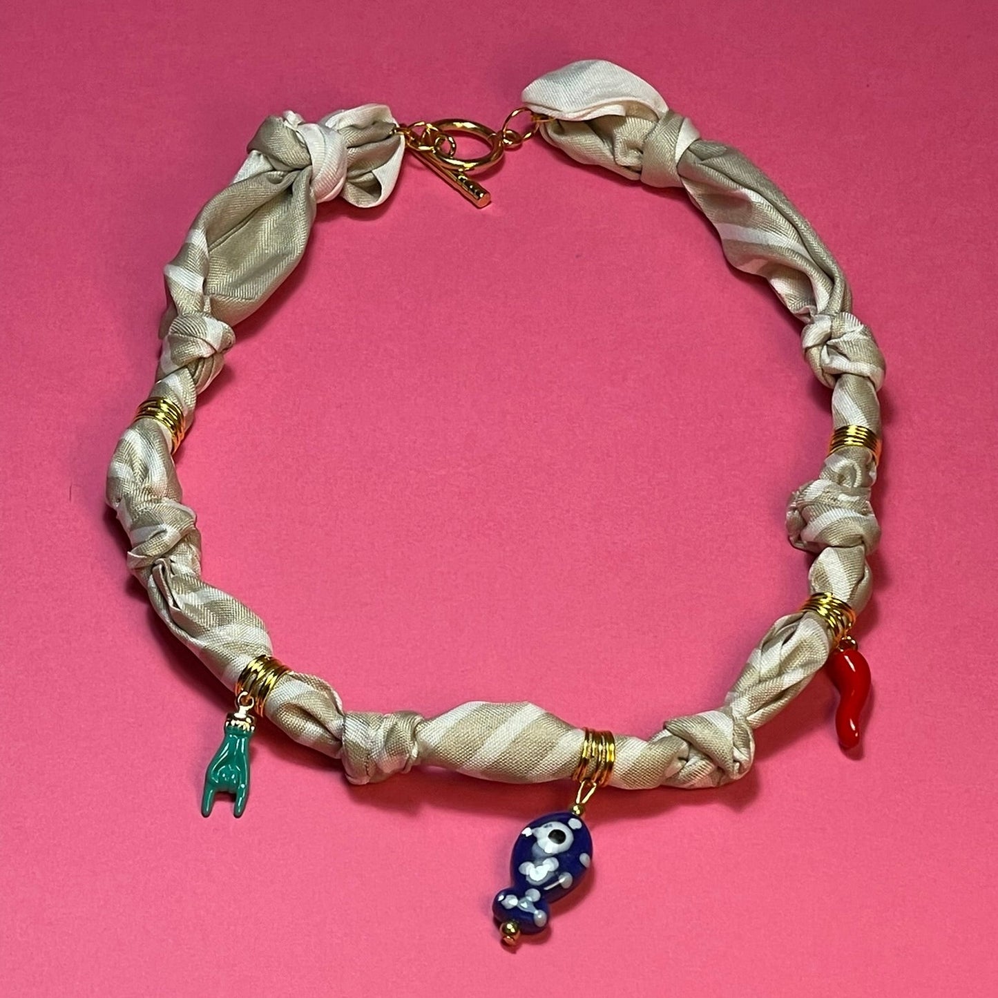 Collar artesanal con dije dorado y pañuelo trenzado, diseño bohemio hecho a mano por Hilma.