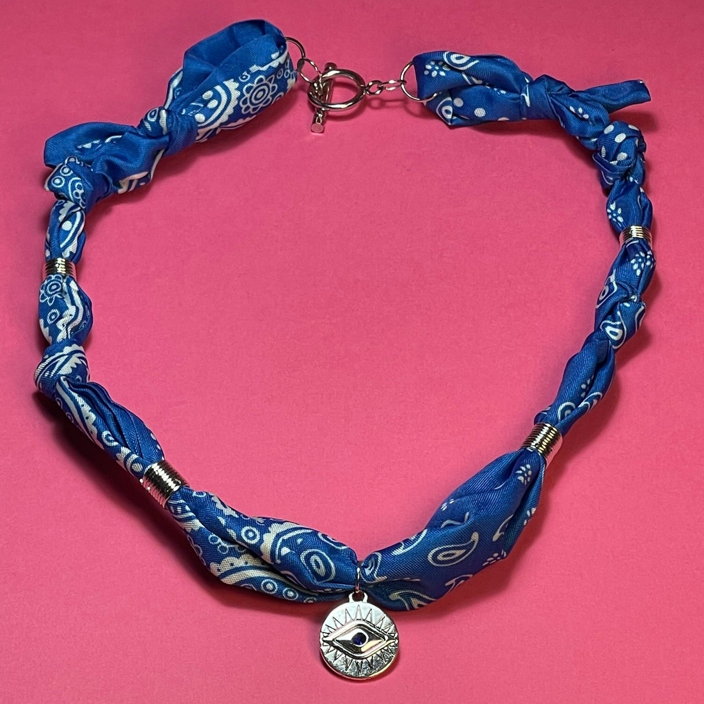 Collar artesanal con dije dorado y pañuelo trenzado, diseño bohemio hecho a mano por Hilma.