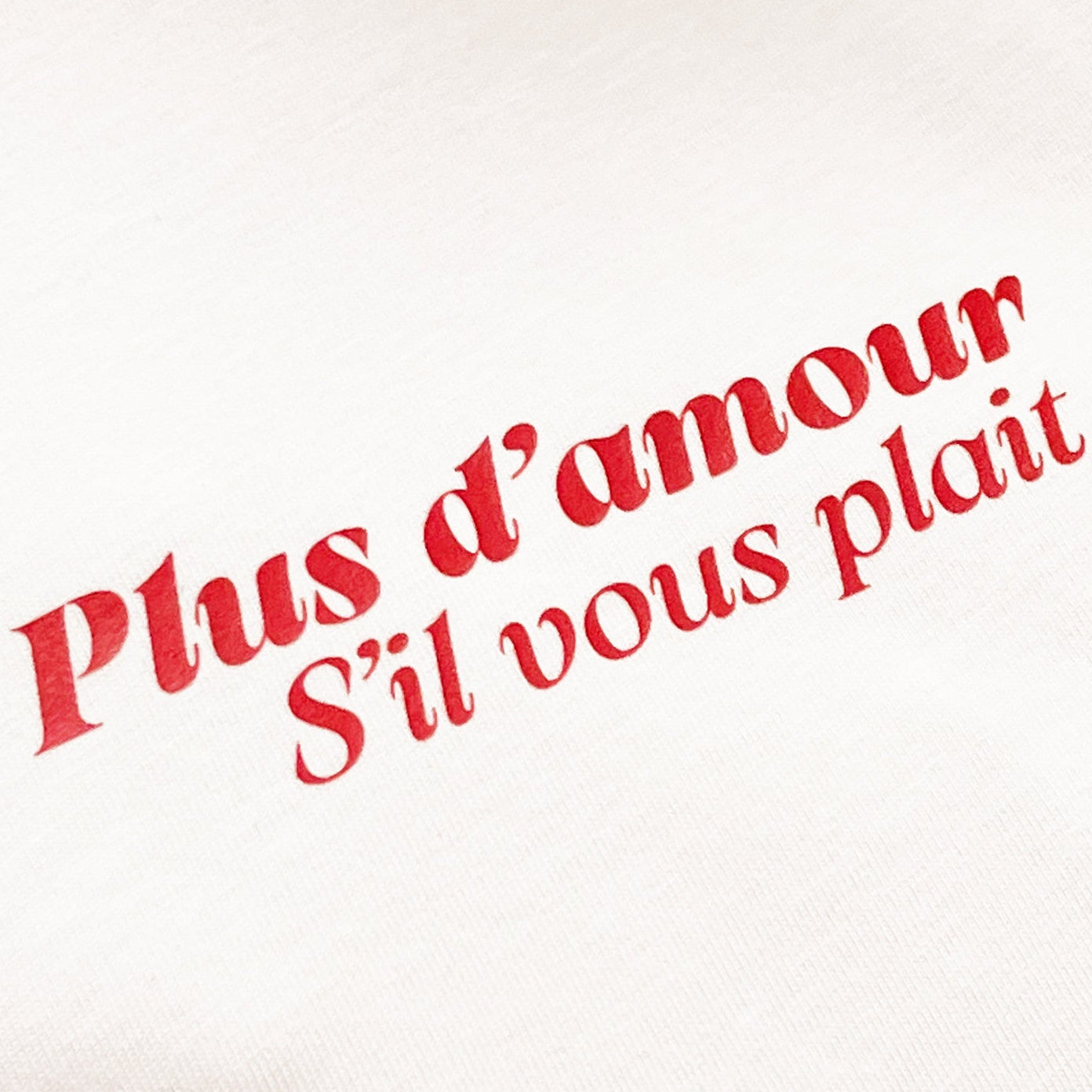 Detalle camiseta beige de algodón con mensaje Plus d'amour s'il vous plait en rojo Hilma Studio
