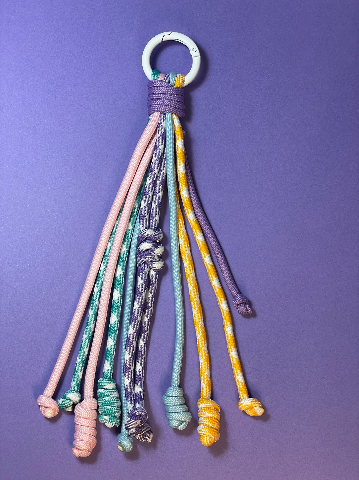 Llavero artesanal colorido con colgantes decorativos y cordones.
