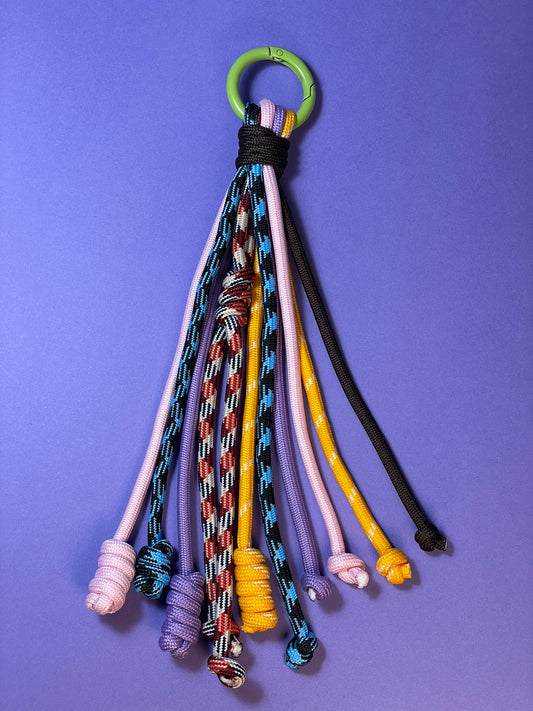 Llavero artesanal colorido con colgantes decorativos y cordones.