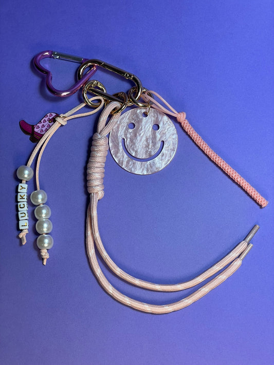 Llavero artesanal colorido con colgantes decorativos y cordones.