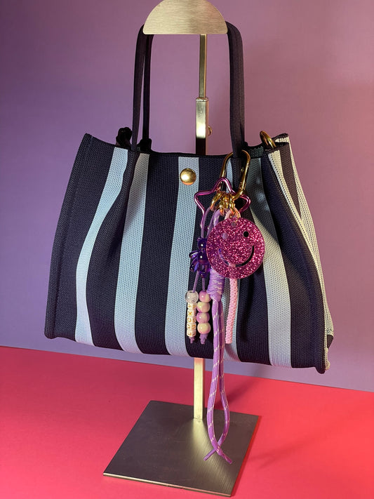 Llavero artesanal colorido con colgantes decorativos y cordones.