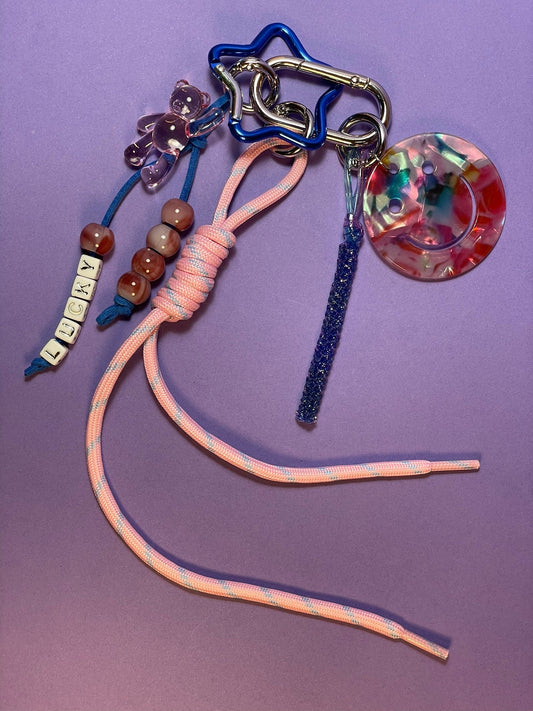 Llavero artesanal colorido con colgantes decorativos y cordones.