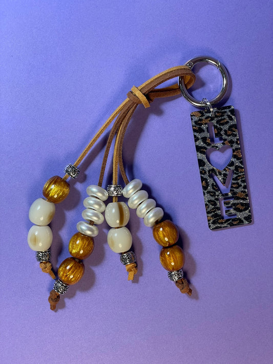 Llavero artesanal colorido con colgantes decorativos y cordones.