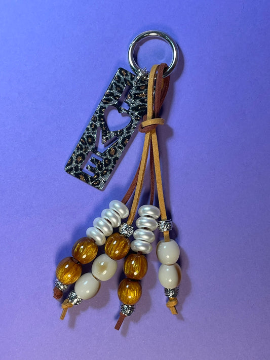 Llavero artesanal colorido con colgantes decorativos y cordones.