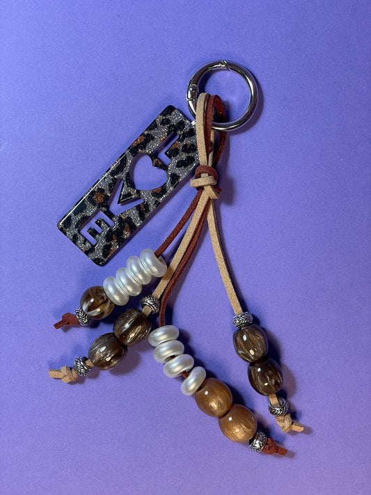 Llavero artesanal colorido con colgantes decorativos y cordones.