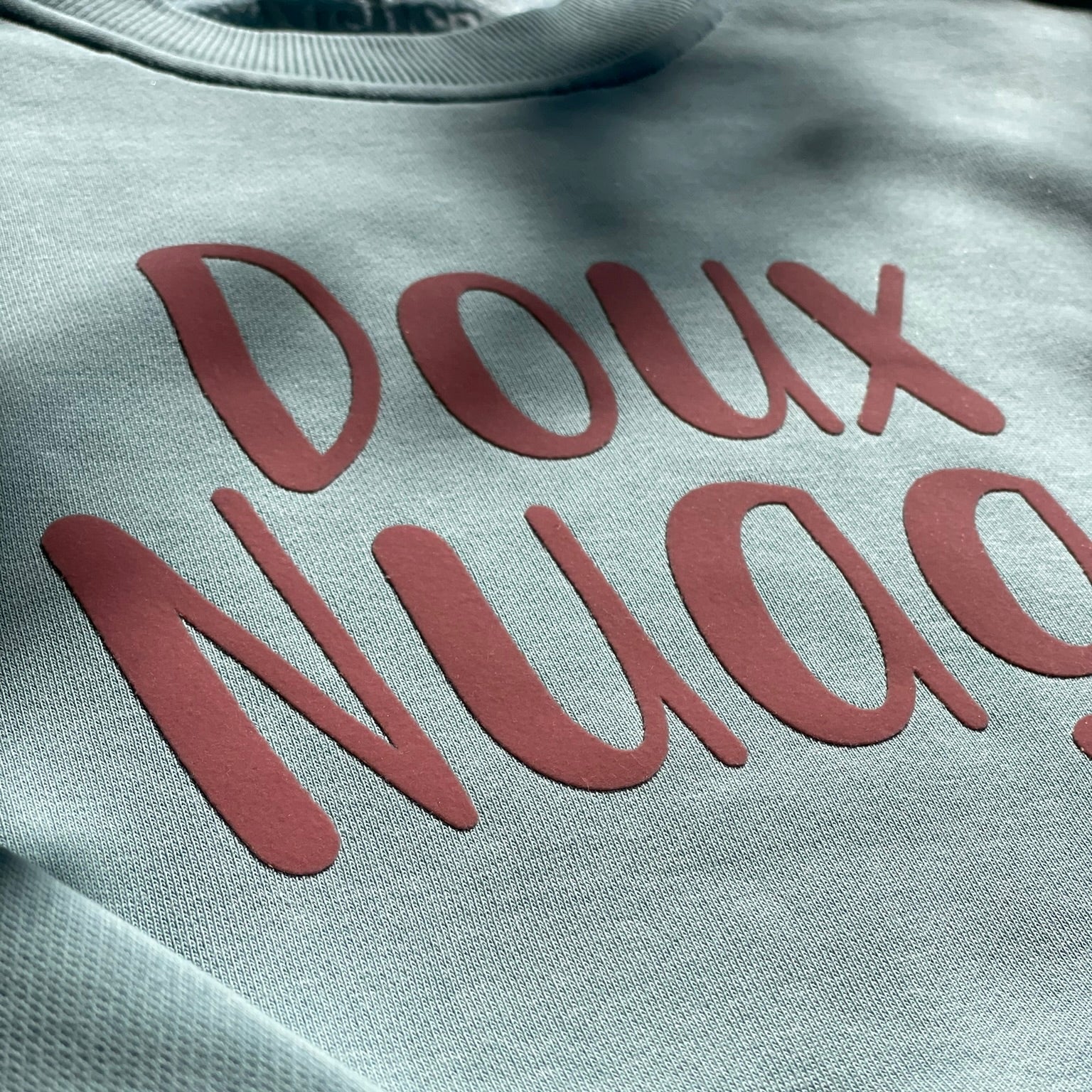 Detalle sudadera azul de algodón con mensaje en terciopelo rosa