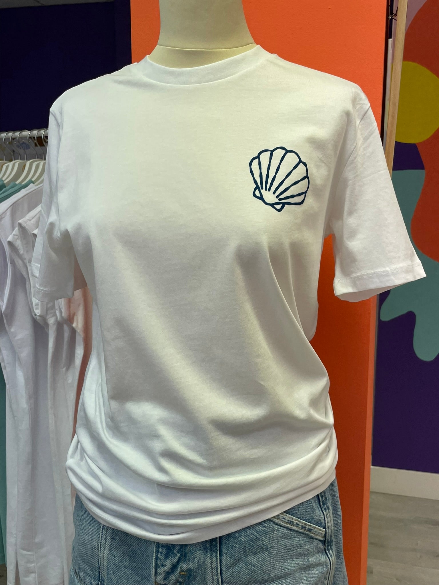 Camiseta unisex blanco de algodón orgánico con un dibujo de conchas marinas y fondo marino en azul terciopelo